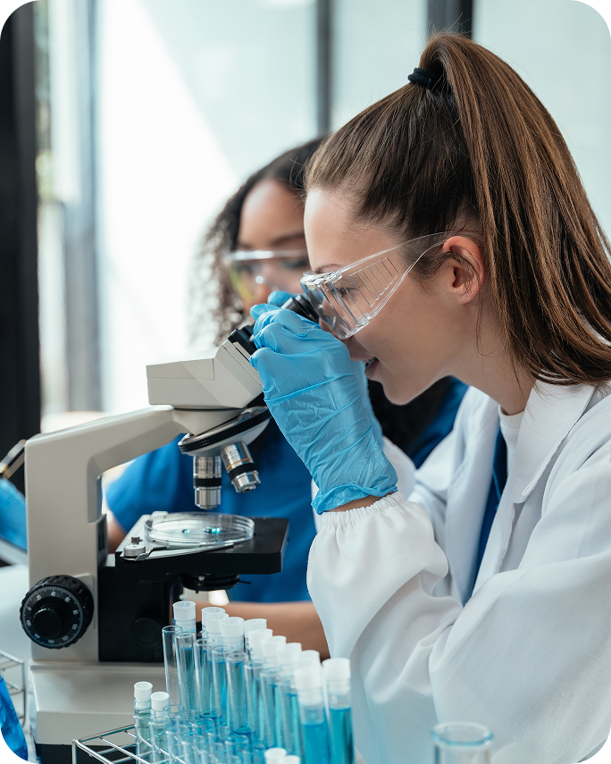 Ricercatrice osserva al microscopio in laboratorio durante lo sviluppo e i controlli scientifici dei farmaci equivalenti Mylan Viatris, garanzia di qualità e sicurezza.